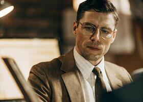 a man in glasses and a suit is looking at something photo