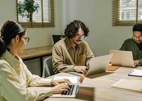 three people working on laptops in an office photo