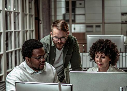 three people working on a computer in an office photo