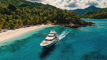 A luxurious yacht glides through clear turquoise waters near a pristine sandy beach lined with palm trees. Lush mountains rise in the background, creating a serene tropical atmosphere photo