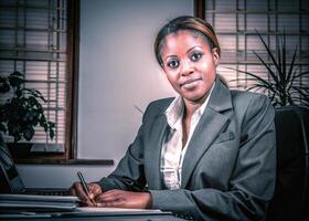 a woman in business suit sitting at a desk photo