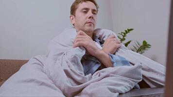 Man uses a heater and blanket while working from home to stay warm during the energy crisis and continue his work. video