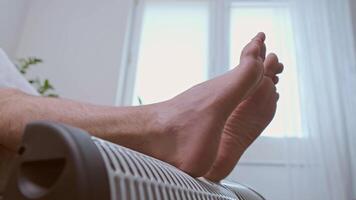 Man uses a heater to warm up, coping with the cold during the energy crisis and rising electricity prices. video