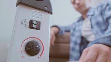A man turns on a heater to warm up in a cold room, using it during an energy shortage. video