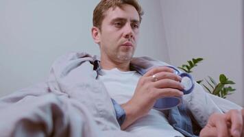 Freelancer stays warm with a cozy blanket and hot tea while working on the computer during an energy crisis. video