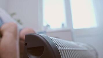 Man warms his feet on a heater during the energy crisis, trying to cope with high utility rates and energy shortages. video