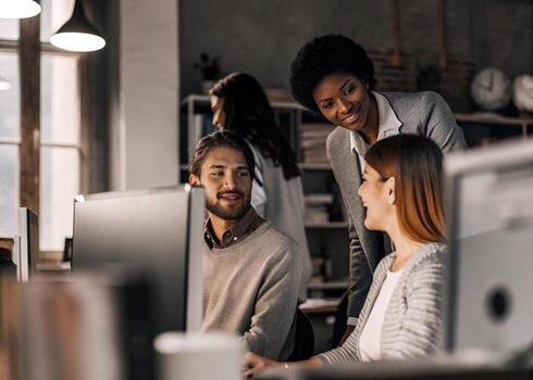 three people working on computers in an office photo