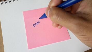 Footage of an illustration of writing the word dont do it on colored paper. Hand activity holding a pen to write the word dont do it video