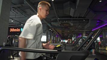 A handsome young Asian man is seen doing intense printed and jogging on a treadmill in the gym. fast running and sprinting. Slow motion video