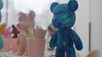 Several freshly hand-painted figurines in the shape of bears are standing on the artist's desk in studio, waiting to be dried before they can be sold. video