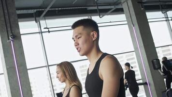 Athletes communicate with each other in friendly and positive manner during warm-up process, while walking on treadmill at gym. video