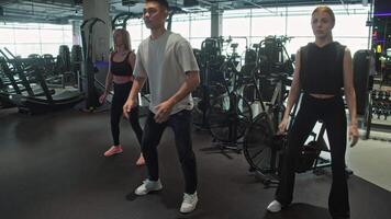 Diverse group of athletes, are engaged in the process of preparing for their workout by performing squats in the gym. Slow motion video