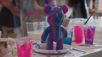 Viscous blue and purple paint drips from decorative sculpture created at art lesson. sculpture was made using epoxy paint in classroom with group of children. video