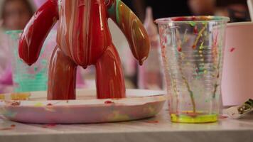 A red, viscous liquid paint drips from a decorative statue that was created in an art class. statue was made using epoxy paint in group activity for children. video
