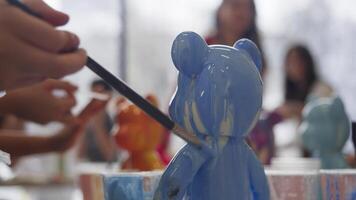 Using a brush, the sculptor carefully adjusts the distribution of paint over the decorative sculpture as they create it in an art class. video