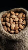 Almond nut in brown beige sack material organic food un cook and deep grey background photo