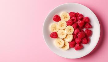 Fresh tropical banana slice and raspberry organic fruit on white plate in pink background photo