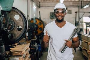 portrait african black worker happy smiling handle big wrench service work in metal factory workshop photo
