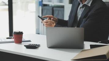 A man in a suit is using his phone while sitting at a desk video