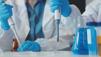 Two people in lab coats and gloves are working on a test tube video