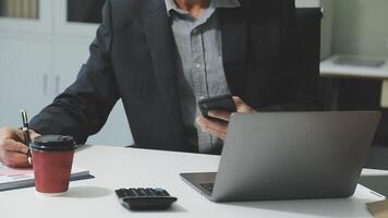 A man in a suit sitting at a desk with a laptop and a cup of coffee video