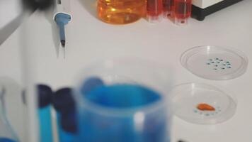 A laboratory table with a microscope, a glass vial and a bottle of liquid video