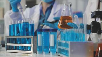 A group of people in lab coats and gloves are working on a test tube video