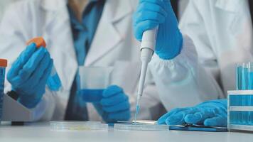 Two people in lab coats and gloves are working on a test tube video