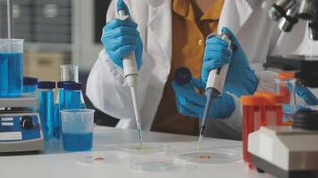 A person in a lab coat is holding a pipette video