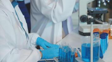 Two people in lab coats and gloves working on a test tube video