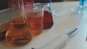 A laboratory table with several bottles and a syringe video