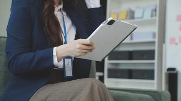 A woman in a business suit is holding a tablet video