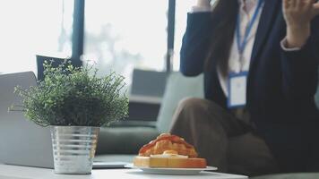 A woman in a business suit sitting at a table with a laptop video