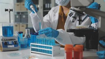 A person in a lab coat and gloves is working on a test tube video