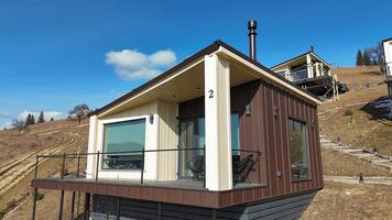 Modern hillside cabin with large windows and balcony, stylish architectural design blending with nature, perfect getaway for relaxation and scenic views video
