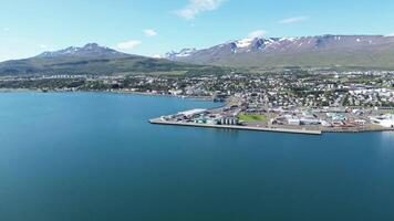Coastal port city with snowy mountains in backgraound aerial video