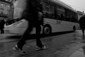 A blurred city scene with pedestrians and a bus. photo