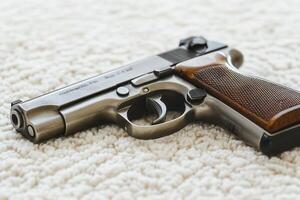 A metallic handgun with wooden grip on a textured surface. photo