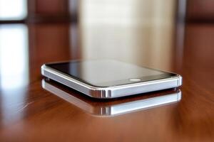 A smartphone resting on a polished wooden surface. photo