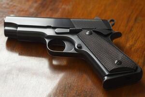 A close-up of a semi-automatic handgun on a wooden surface. photo