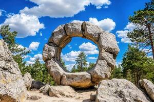 A large stone circle surrounded by trees and blue sky. photo