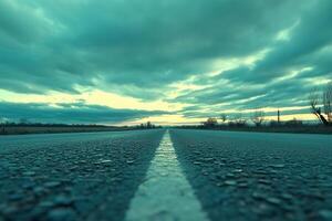 A low-angle view of a deserted road under cloudy skies. photo