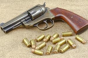 A revolver with bullets on a textured surface. photo