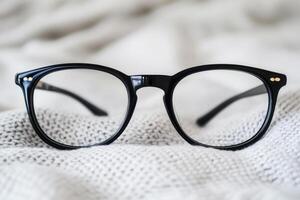 Black eyeglasses resting on a textured fabric surface. photo