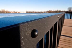 Close-up of a railing by a serene waterfront. photo