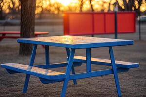 Blue picnic table at sunset in a park setting. photo