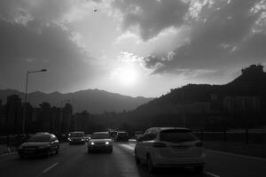 Black and white cityscape with cars and mountains at sunset. photo