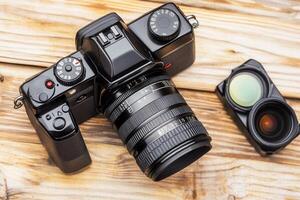 Camera with lens and viewfinder on wooden surface. photo