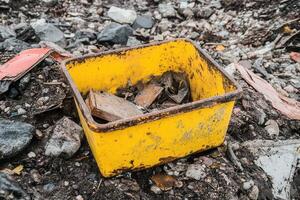 A yellow container filled with debris on the ground. photo