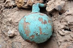 A weathered turquoise spherical object on a wall. photo